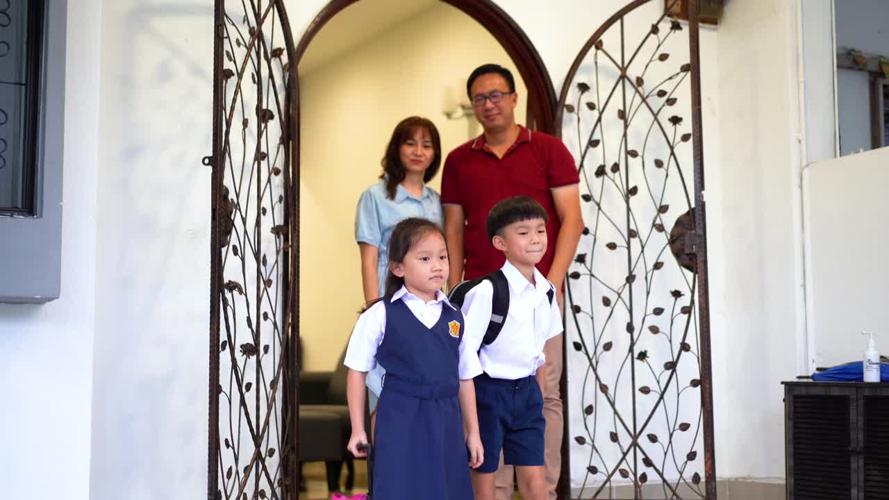 年幼的兄弟姐妹们穿着校服离开家去上学视频素材