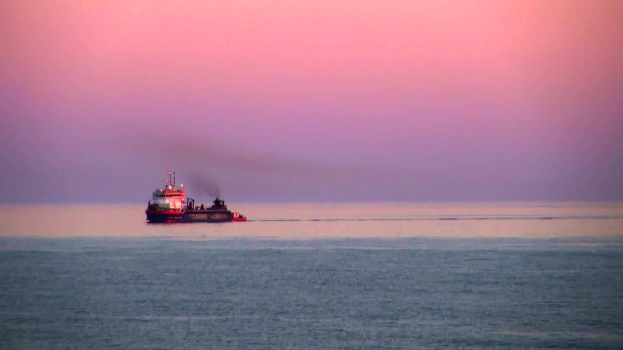 在西班牙的加的斯，日落时分，粉红色的天空映衬着泊在海上的轮船发出的美丽的蒸汽视频素材