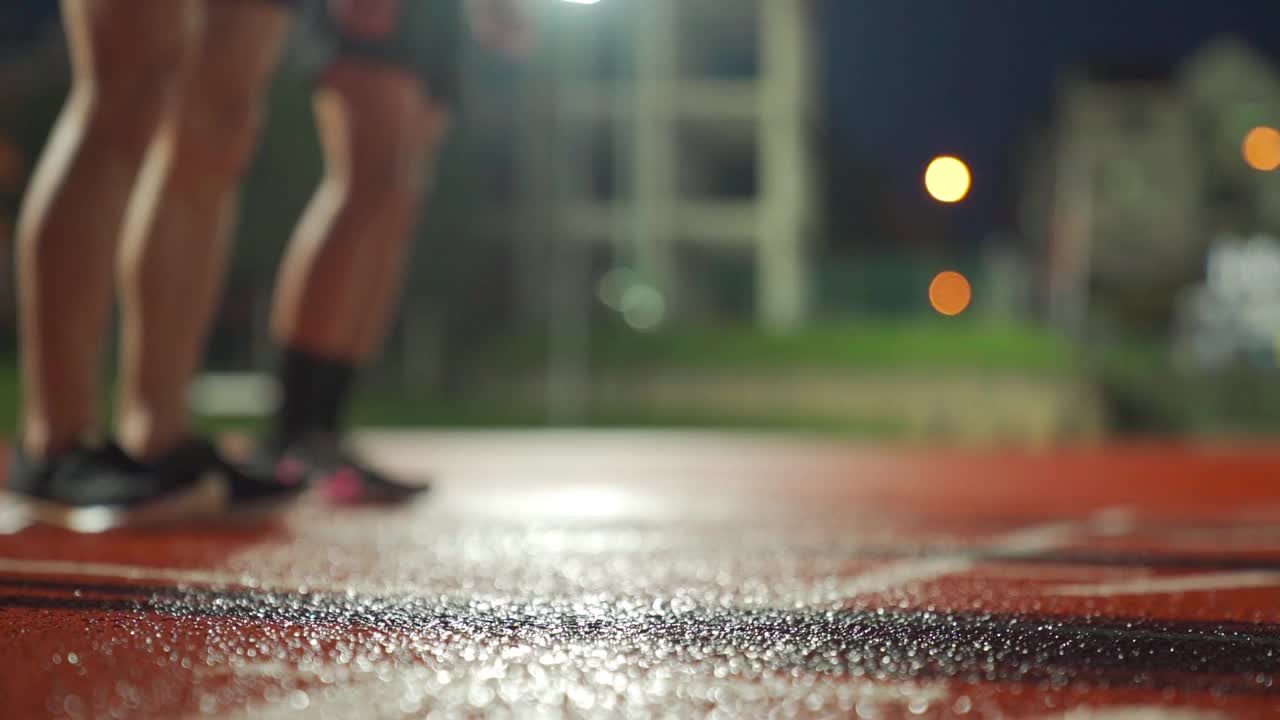 慢镜头亚洲华人男运动员排队准备起跑线在男子田径赛雨深夜在体育场视频素材