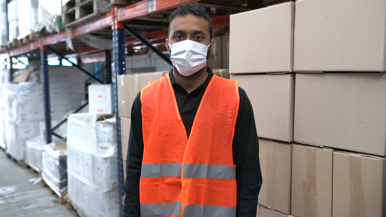 一名戴着口罩在仓库工作的男子的肖像视频素材