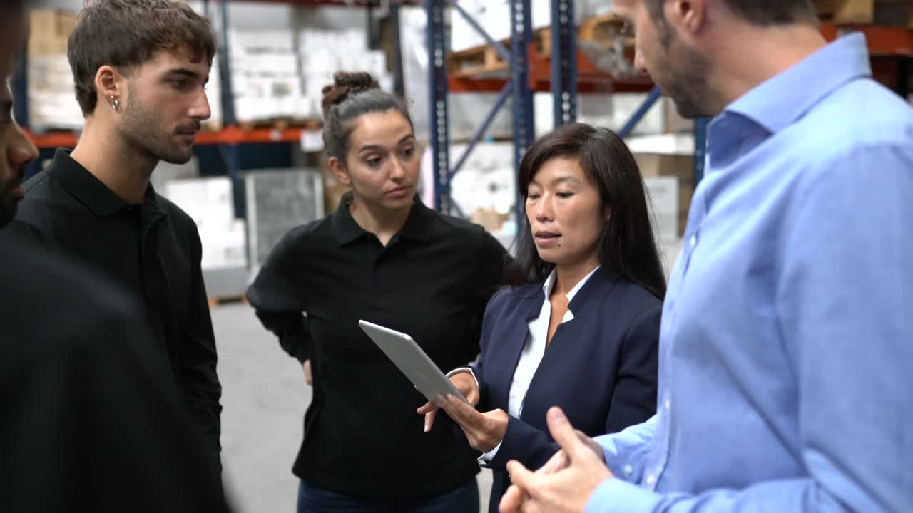 女商人在仓库与工人讨论发货时间表视频素材