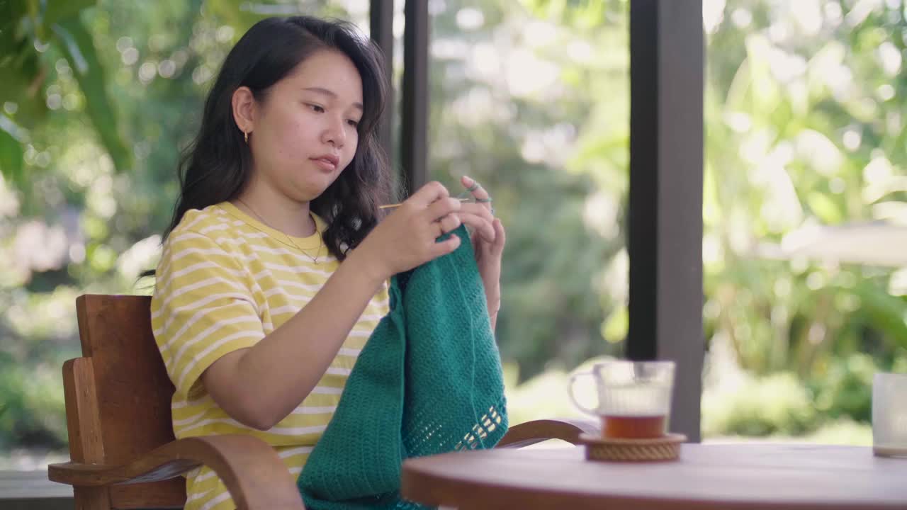 用绿色纱线钩针编织的女人。视频下载