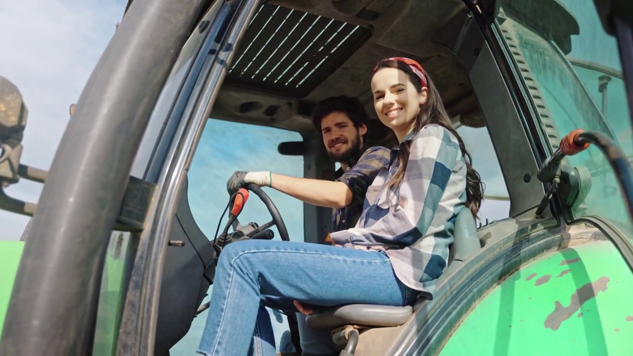 一个年轻的女人坐在拖拉机里的男人旁边视频素材