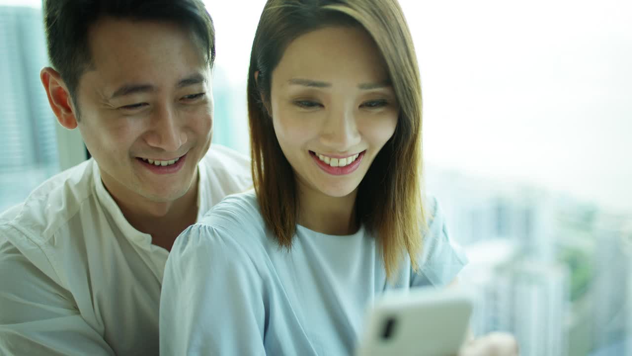 亚洲华人夫妇在智能手机上看照片视频素材