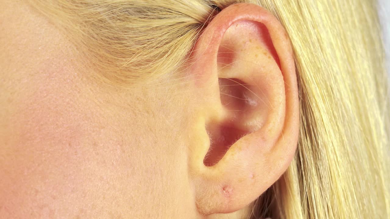 一个金发女人用手捂着耳朵想听得更清楚——特写镜头视频下载