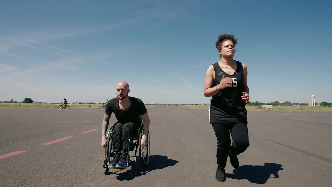坐在轮椅上的男人和一个在户外跑步的女人一起锻炼视频素材
