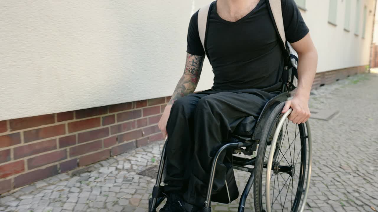 一个坐着轮椅在人行道上行走的残疾人视频素材