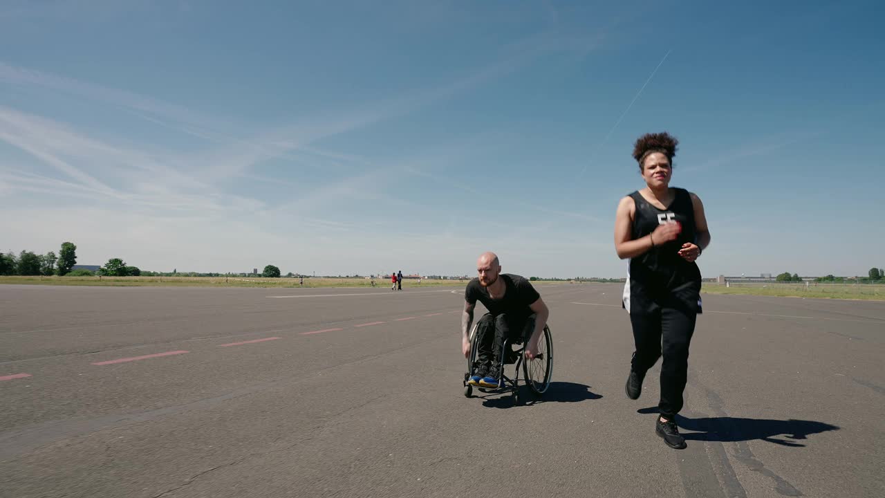 一个女人和一个坐轮椅的残疾人一起跑步视频素材