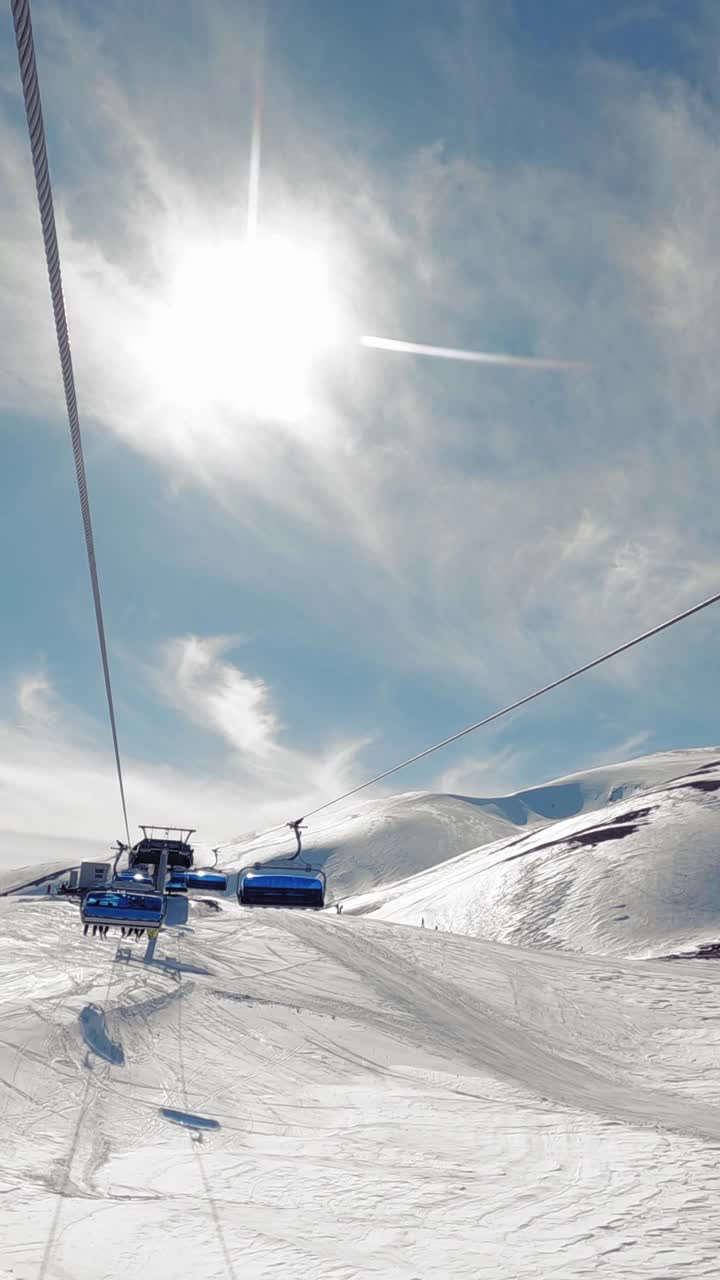 坡乘滑雪椅升降于阳光明媚的冬日，垂直方向视频下载