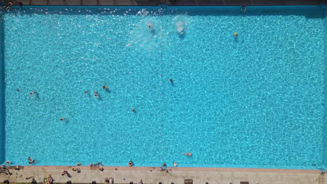 俯瞰公共城市游泳池，在阳光明媚炎热的日子里人们游泳视频下载