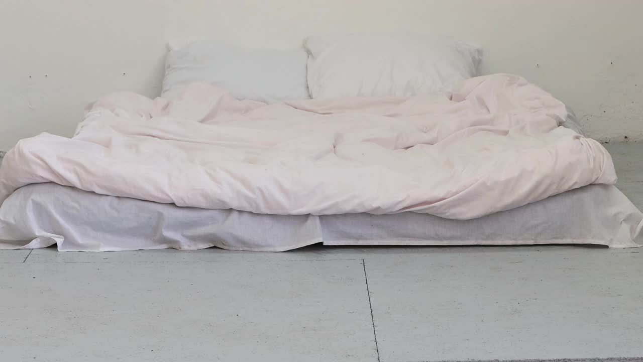 粉红色的床单、床枕、床单和红白玫瑰贴在墙上。空白的床上用品。4 k的决议视频下载