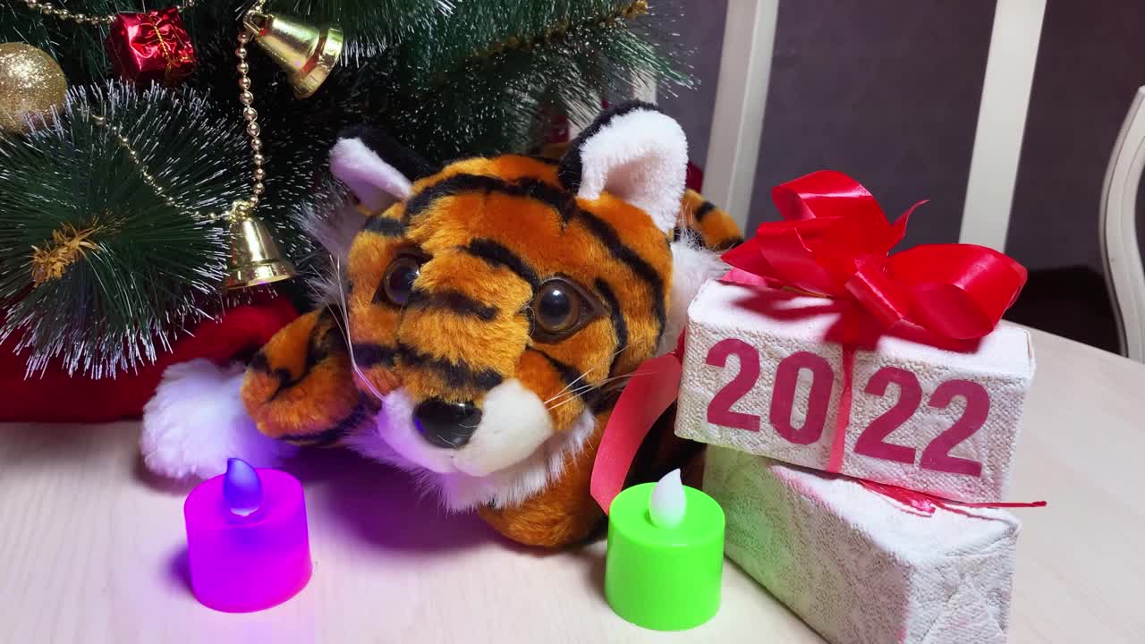 房间里的新年树旁，白色的桌子上放着“2022”字样的蜡烛和礼品盒。视频下载
