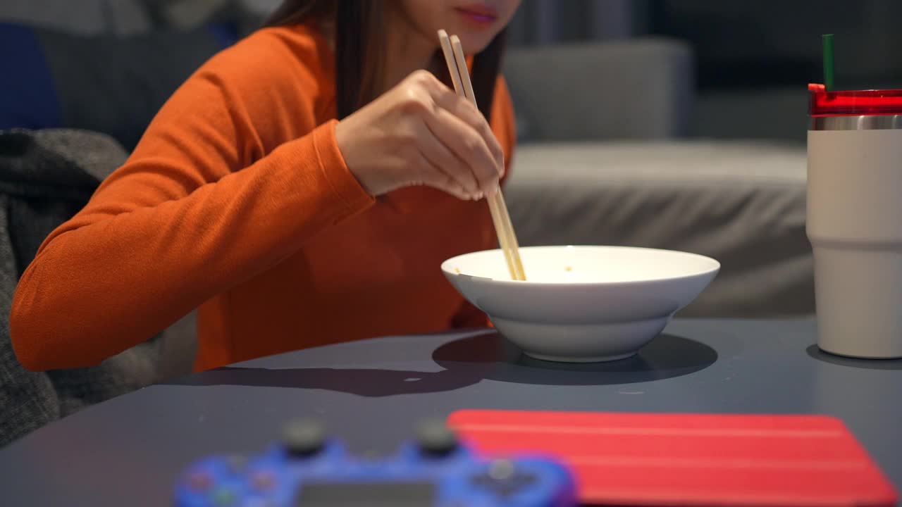 4K亚洲女人晚餐吃中国面条看电视电影视频素材