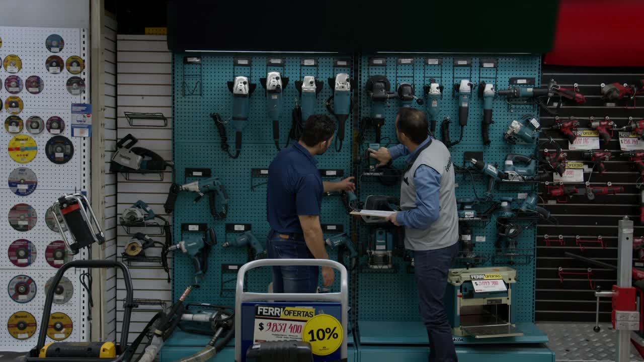 一位拉丁美洲的顾客在一家五金店购买工具，与一位指着陈列中的不同工具的售货员交谈视频下载