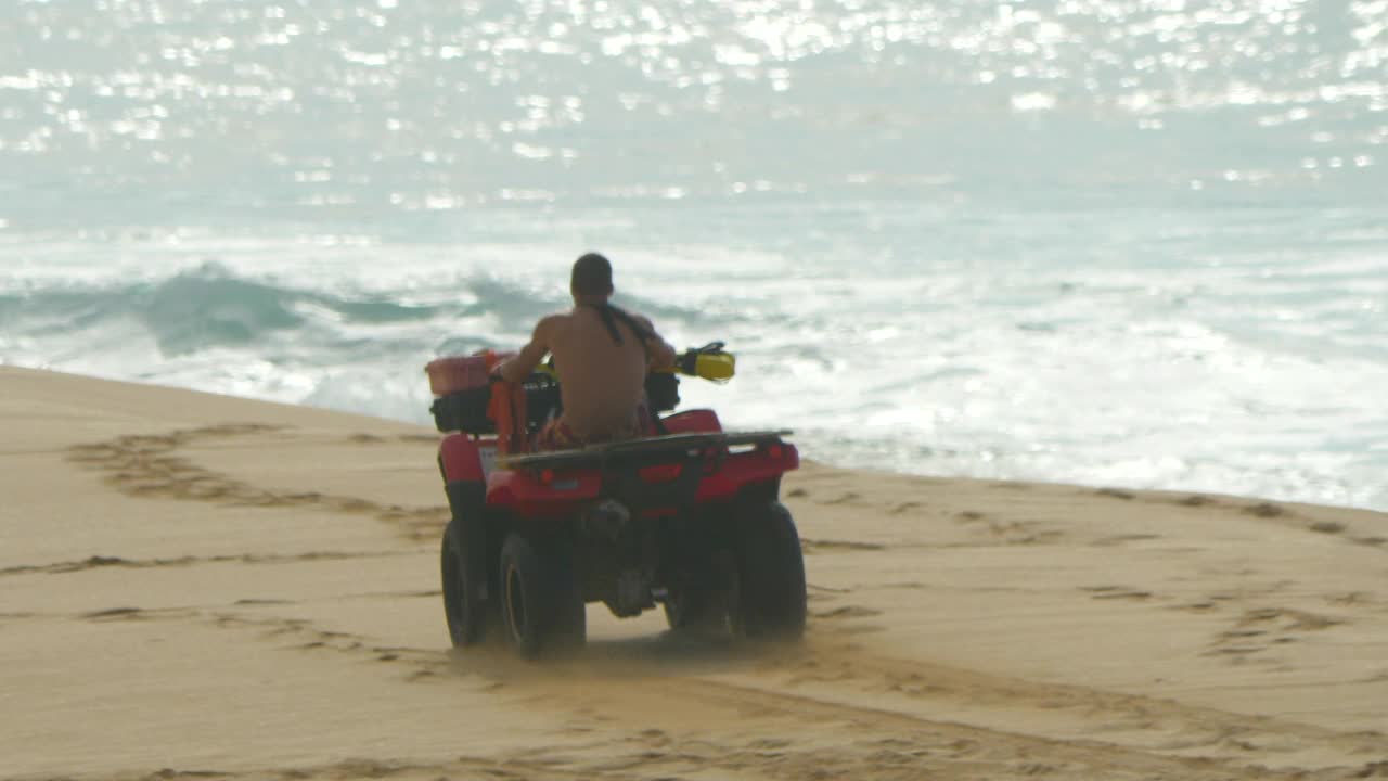 在夏威夷瓦胡岛北岸的管道海滩上，救生员驾驶四驱车。——慢动作视频下载
