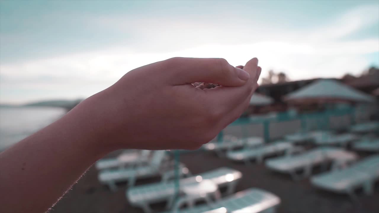 沙滩上的手。特写慢镜头中，沙子从女性手指间流过。视频素材