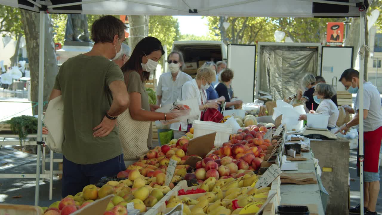 戴着口罩的人们在法国的街头水果蔬菜市场购买视频下载
