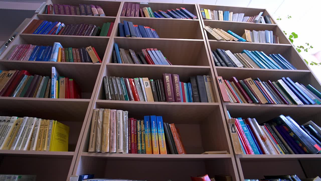 图书馆的书堆放在书架上。图书馆里一排排放着书的书架。教育、学校或大学的学习理念。相机移动回来。视频下载