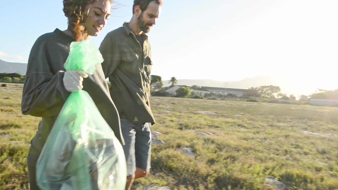 两个微笑的志愿者在田野里捡拾垃圾视频下载