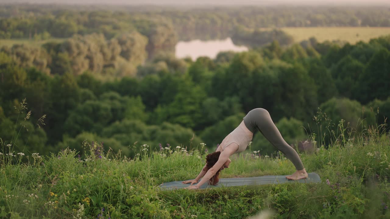 在慢动作中，一名年轻女子在顶部做平衡和伸展的瑜伽练习。身体和灵魂的平静和平衡。身体不停地弯曲视频下载