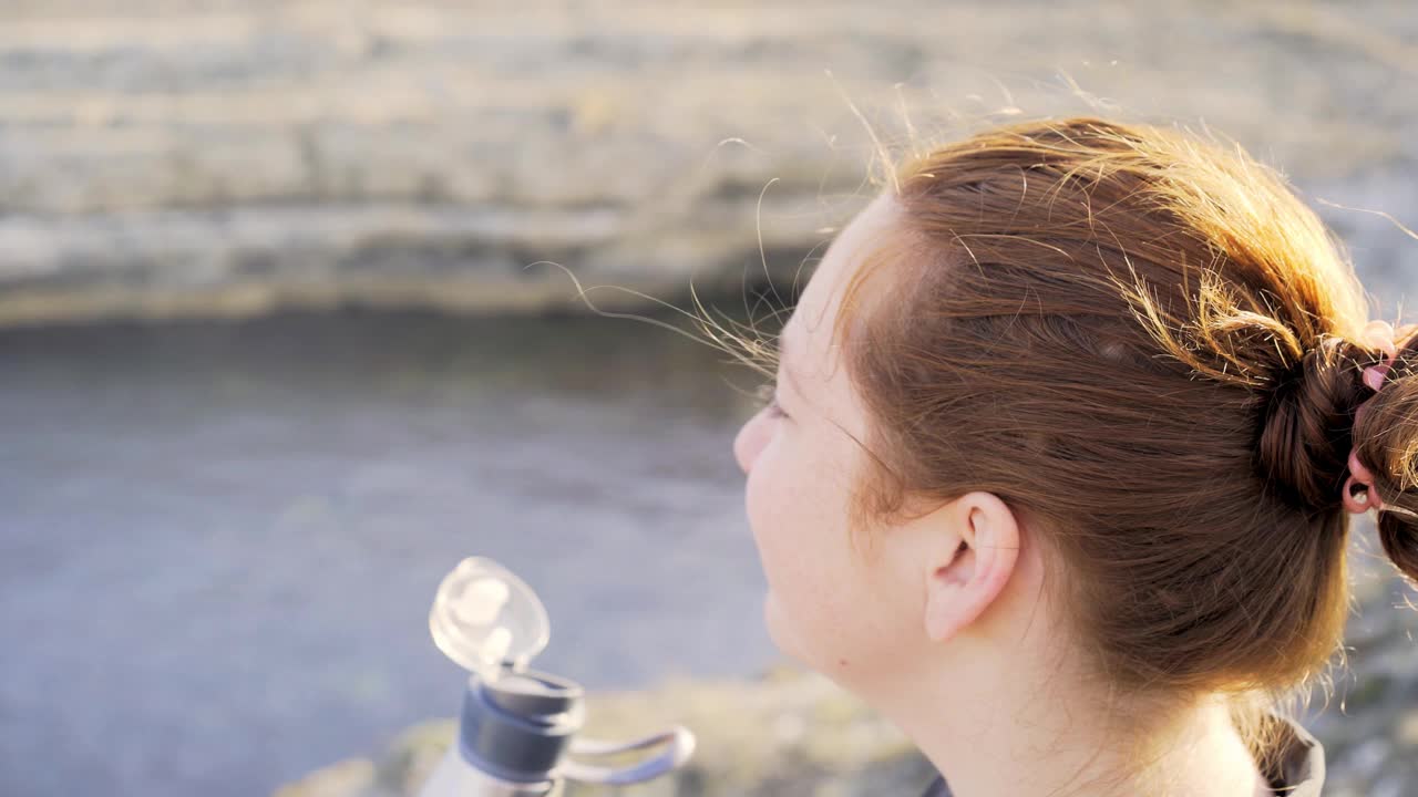 在大洋湾的海岸，一个女人从热水瓶里喝水视频素材