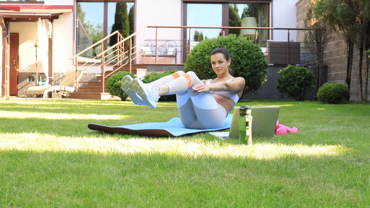 迷人苗条的女孩穿着运动服在户外做腹肌锻炼。健康的生活方式视频素材