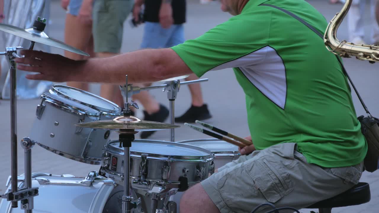 鼓手与鼓槌热身在城市街道的背景在晚上。他在鼓上演奏爵士乐、摇滚和金属音乐。乐队排练干扰4k视频。视频下载