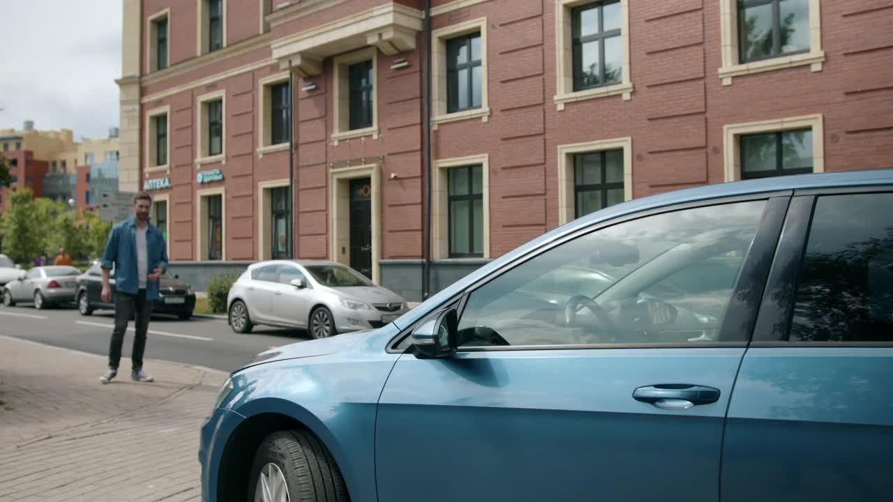 一个司机来到他的蓝色金属轿车，坐在里面，靠近古典风格的建筑视频下载