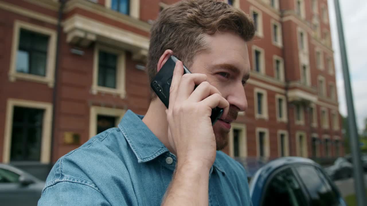 一位年轻迷人的汽车司机，靠着红砖外墙，结束了他的电话交谈视频下载
