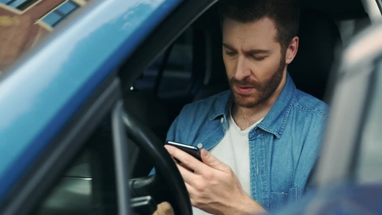 一个留着胡子的欧洲男人坐在开着车门的驾驶座上打电话视频下载