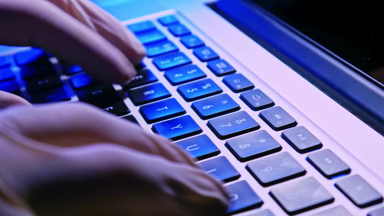 医生戴着白色医用手套在笔记本电脑上打字。视频下载
