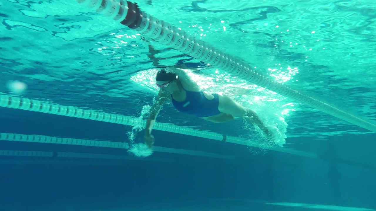 水下射击:适合美丽的游泳运动员在游泳池做圈。职业女运动员游泳速度很快。准备创造世界冠军纪录。彩色艺术风格跟踪镜头视频下载