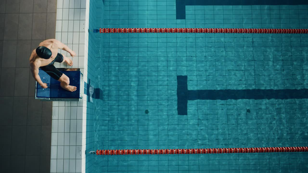 鸟瞰图男游泳运动员跳水和游泳在奥林匹克游泳池。专业运动员在锦标赛上表演，蝶式表演。赢的决心。电影追踪慢动作视频素材