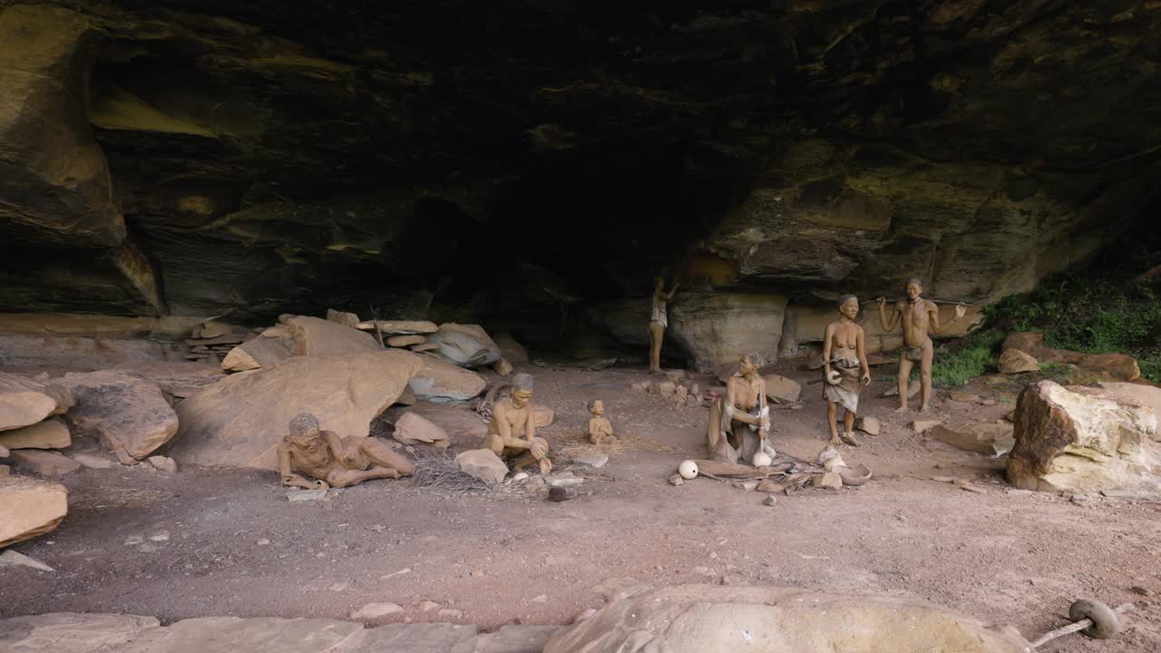 在南非夸祖鲁-纳塔尔省德拉肯斯堡巨人城堡的主要洞穴中，用平镜拍摄的真人大小的丛林人模型场景，描绘了一个丛林人家庭的生活视频素材