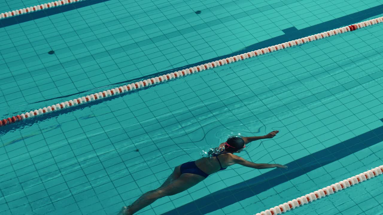 美丽的女子游泳运动员使用前爬泳，自由泳在游泳池。职业运动员决心赢得冠军。电影慢动作，时尚的颜色，艺术高角度跟踪镜头视频素材