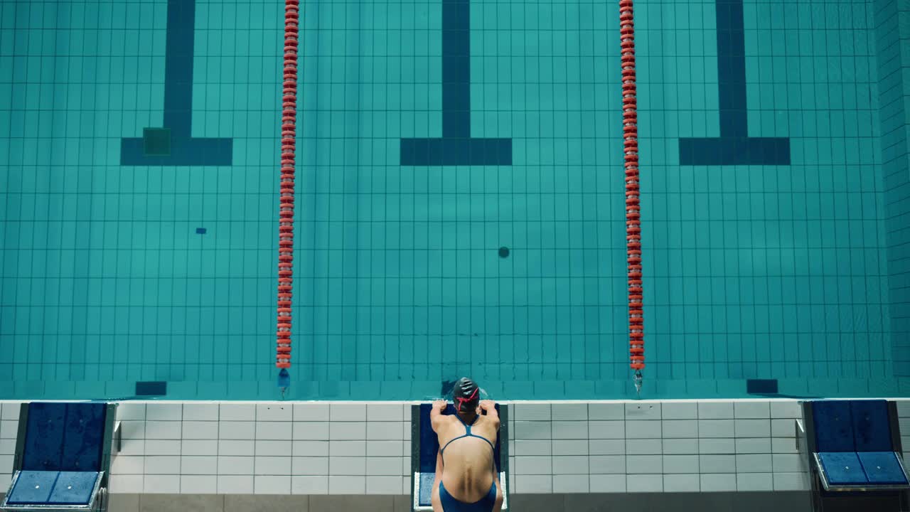 鸟瞰图:美丽的女游泳运动员在游泳池跳水。专业运动员优雅的跳跃。人训练决心赢得冠军。电影慢动作与时尚的颜色视频素材