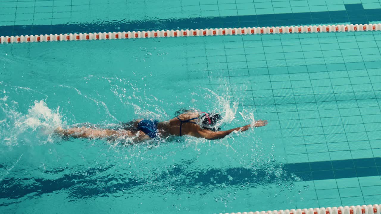 美丽的女子游泳运动员使用前爬泳，自由泳在游泳池。职业运动员训练以赢得冠军。电影慢动作，时尚的颜色，艺术高角度跟踪镜头视频素材