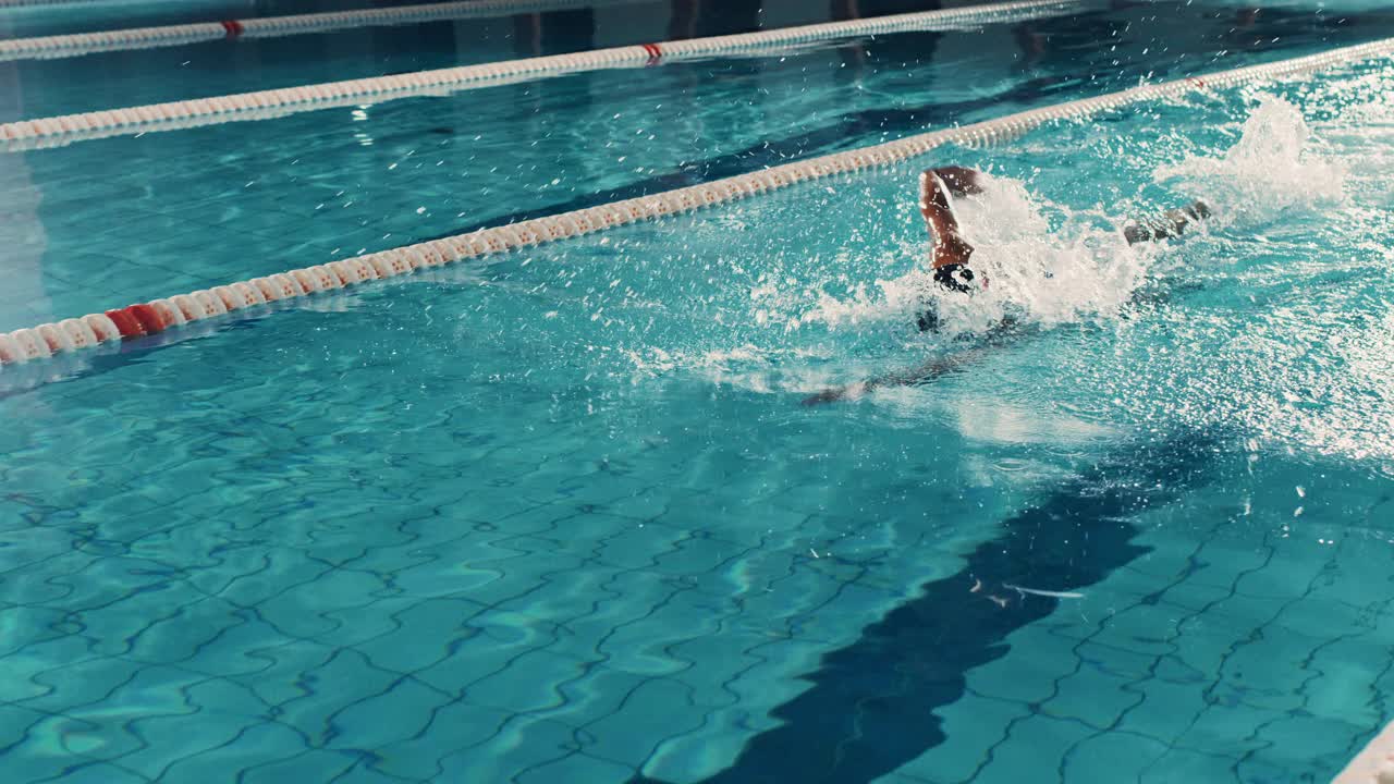 美丽的女子游泳运动员使用前爬泳，自由泳在游泳池。职业运动员决心赢得冠军。电影慢动作，时尚的颜色，艺术跟踪宽镜头视频素材
