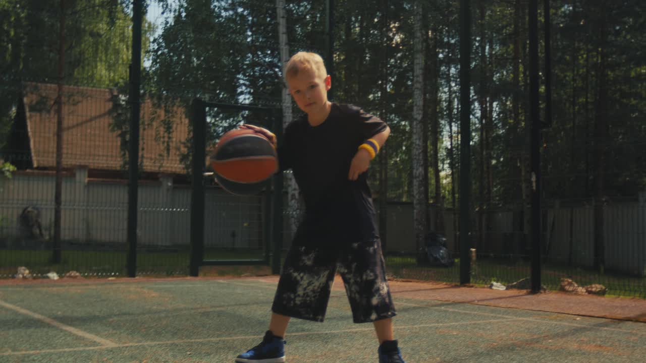 儿童篮球运动员在室外篮球场上练习控球技巧。健康的运动儿童生活方式视频下载