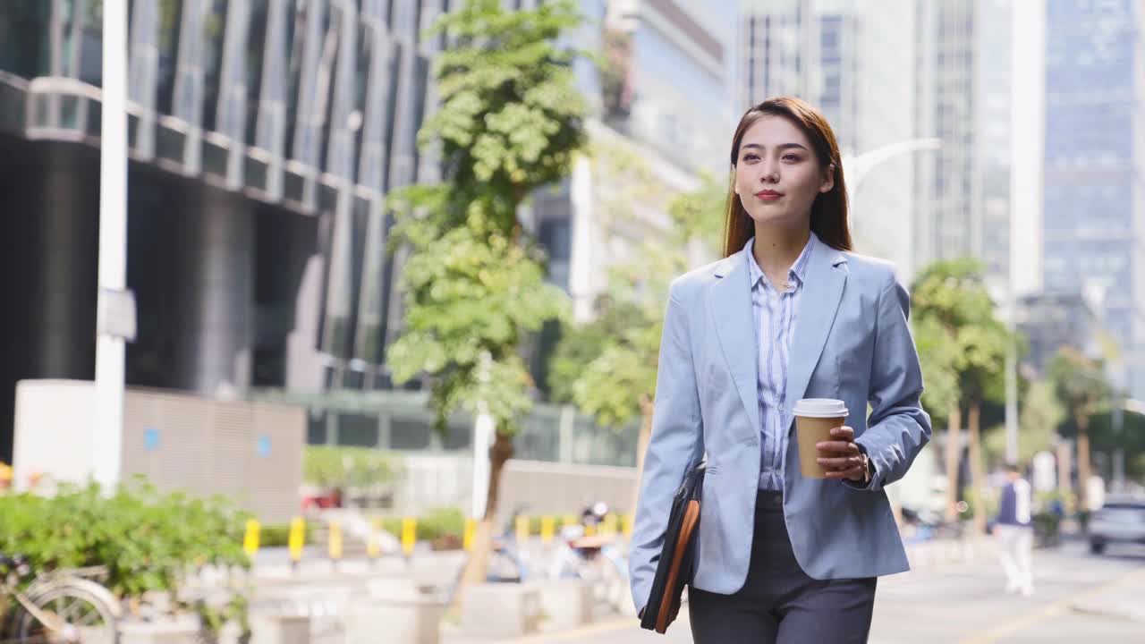 年轻的亚洲女商人走在现代城市的中央商务区视频下载