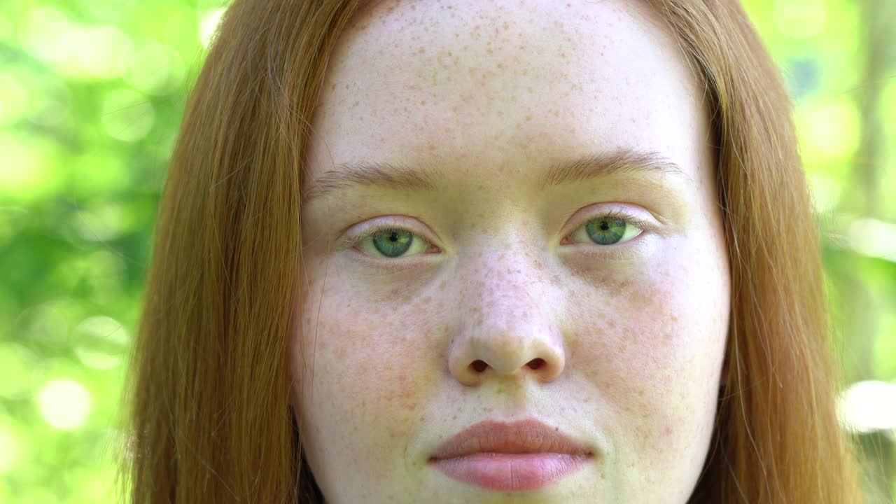 在一片阳光灿烂的草地上，画一个带着红头发和雀斑的微笑年轻女子。视频下载