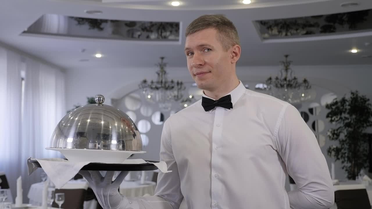 在一家餐馆里，一名男服务员拿着一个盛有盖菜的托盘。视频下载