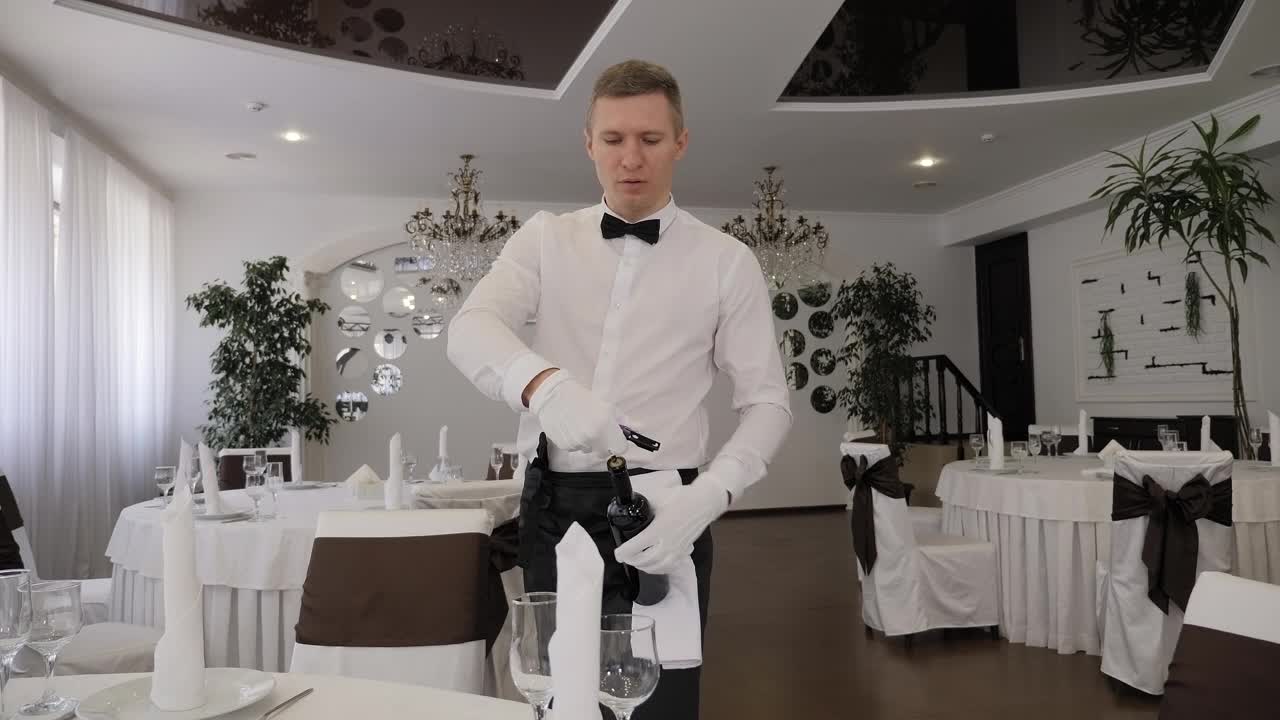在一家餐厅，一位男服务员打开一瓶红酒的肖像。视频下载