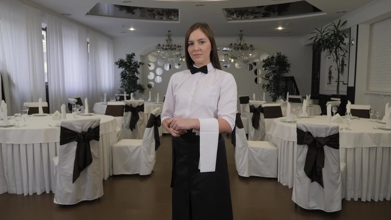 一幅年轻女服务员的肖像，系着围裙，手里拿着一条白毛巾。视频下载