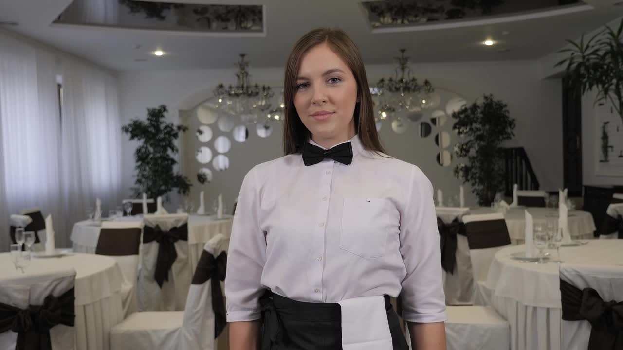 一个餐馆里穿着衬衫打着领结的年轻女服务员的肖像。视频下载