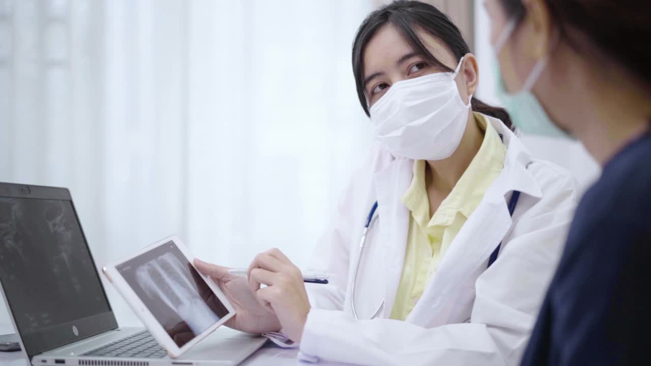 女医生一边解释一边向病人展示平板电脑上的x光照片。视频素材