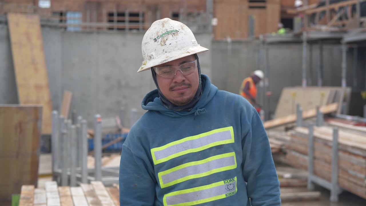 一个西班牙建筑工人的特写，他交叉双臂，微笑着，在镜头前看起来很自信视频下载