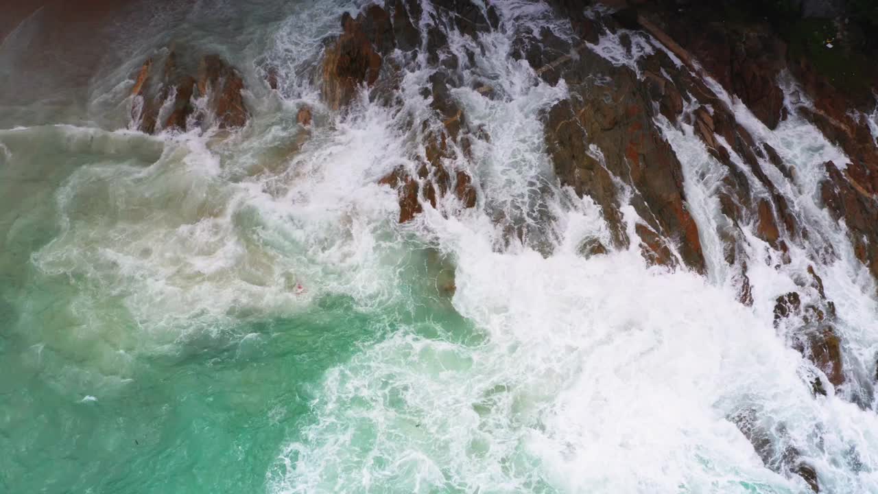 4K无人机从上到下鸟瞰大海，蓝色的海浪拍打在岩石和沙子上。美丽的海水海浪来到海滩视频素材