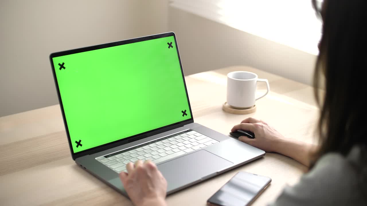 一个女人在用绿色屏幕的笔记本电脑视频下载