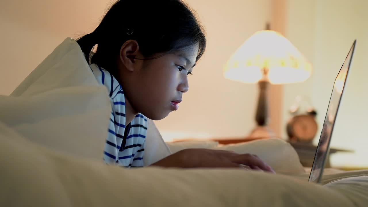 亚洲女孩在卧室里用智能手机社交媒体视频素材